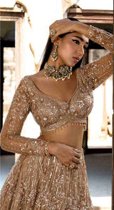 Champagne gold lehenga in sequin, crystal and glass beads. Teamed up with a very chic and smartly fitted choli accentuated with stylish cuts wi
